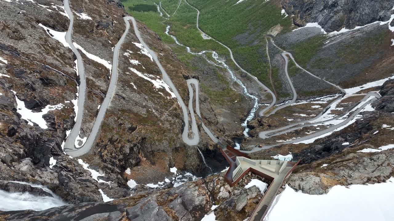 Trollstigen viewpoint - Platform on a cliff with outstanding view of famous trollstigen road in Norway - High angle aerial with spectacular road and river seen in background down below