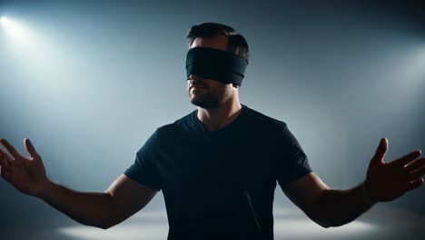 un hombre con los ojos vendados extiende los brazos en una habitación oscura y humeante, encarnando sentimientos de búsqueda, vulnerabilidad e incertidumbre.