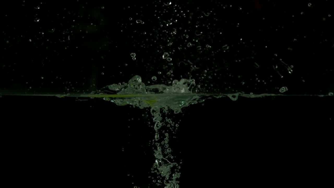 Green apple plunging into water on black background