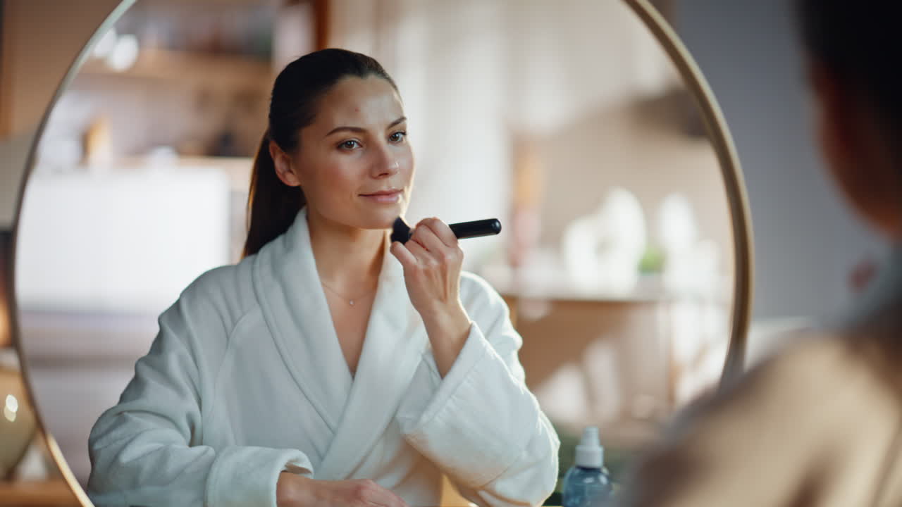 Lady using cosmetic brush on neck at morning routine looking mirror closeup
