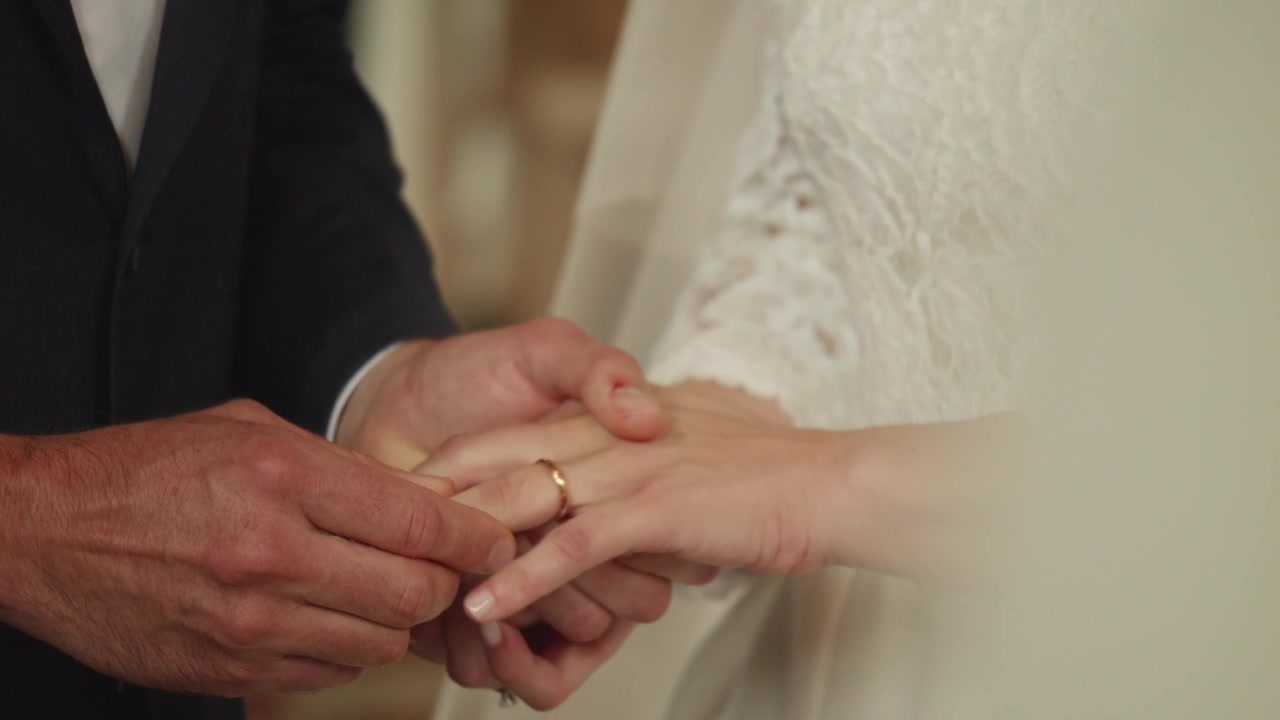 Lo sposo che mette l'anello nuziale al dito della sposa durante la cerimonia. Primo piano intimo che cattura amore, impegno e il momento simbolico dei voti nuziali.