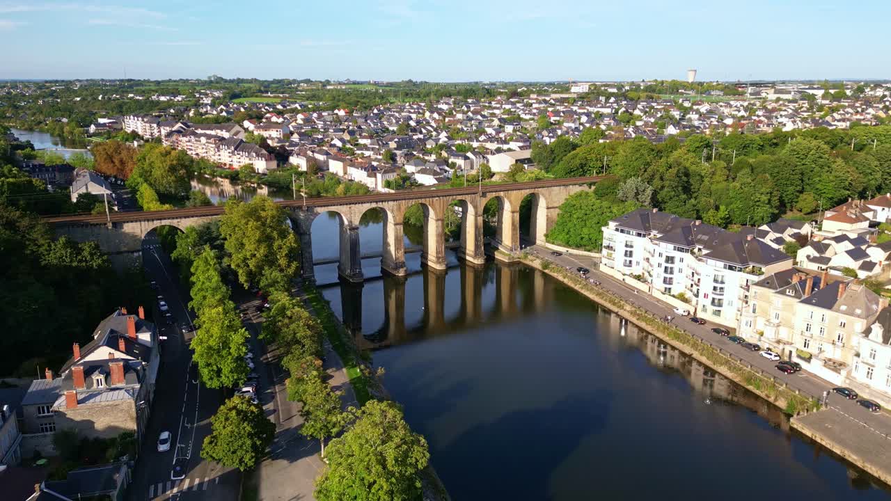 Drone flight over the Mayenne River in Laval moving towards the old viaduct with reflections on the water