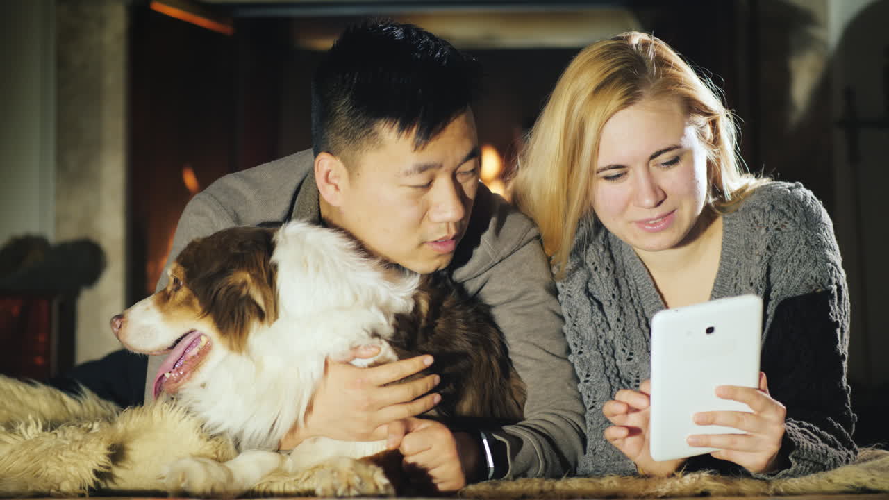 젊은 부부는 개와 함께 벽난로 옆에서 쉬고 있다 03