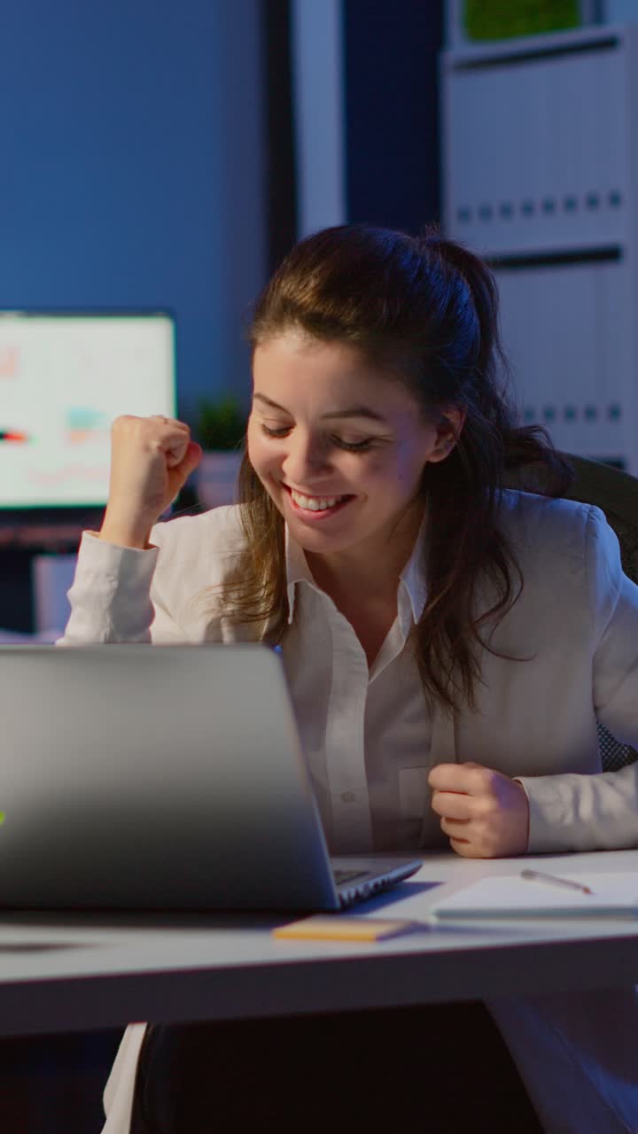 Vertical video: Excited woman winner looking at laptop celebrate online win success