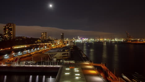 beautiful time lapse long shot of the port of hamburg at night with full moon and many ships and traffic