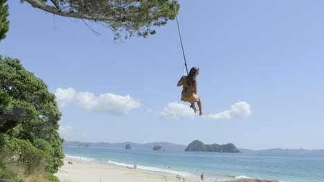 Chica-En-Columpio-De-Cuerda-En-La-Playa-De-Hahei,-Nueva-Zelanda