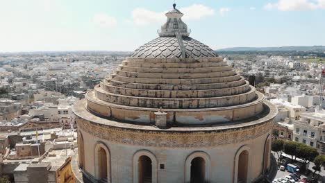 closeup aerial 4k drone footage of the mosta rotunda dome, a roman catholic church, ascending and moving forward to reveal the surrounding city of malta