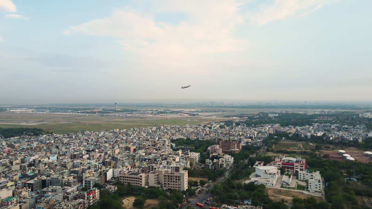 una toma aérea de un avión no tripulado de un vuelo que despega desde el aeropuerto de igi, delhi, volando por encima del paisaje de la ciudad.