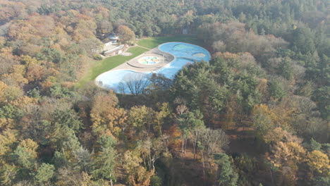 aerial reveal of deserted outdoor swimming pool surrounded by forest