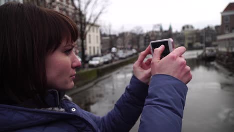 woman tourist takes pictureson on smartphone in amsterdam