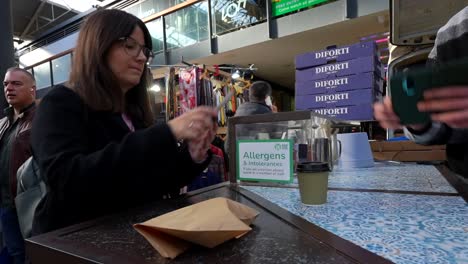 woman paying to the waiter using the phone at spitalfields market, london