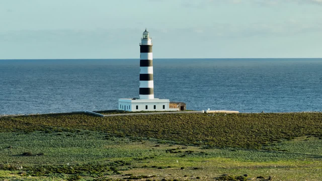 Aerial panoramic fly Illa del Aire lighthouse in Menorca, natural environment of Spain, ocean skyline background