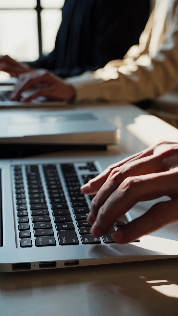 Blurred video still of a student working on a laptop in a sunlit classroom