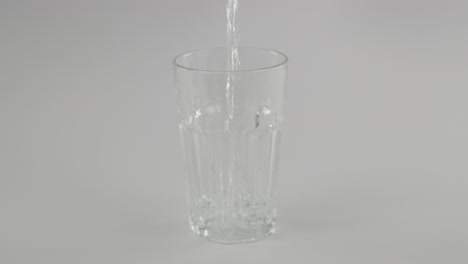 Stilles-Wasser-In-Zeitlupe,-Das-Vor-Neutralem-Hintergrund-In-Klares-Glas-Strömt