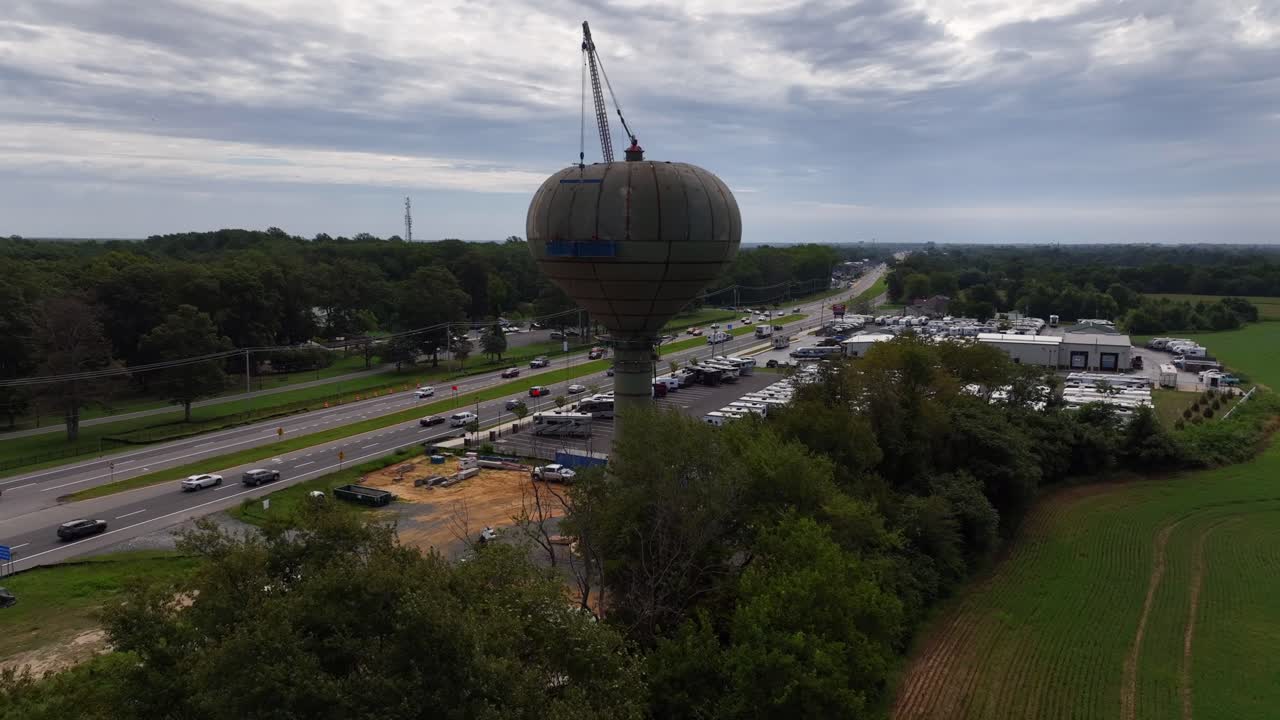 una vista aérea de personas en andamios azules, atadas a una torre de agua mientras están soldando la vieja estructura