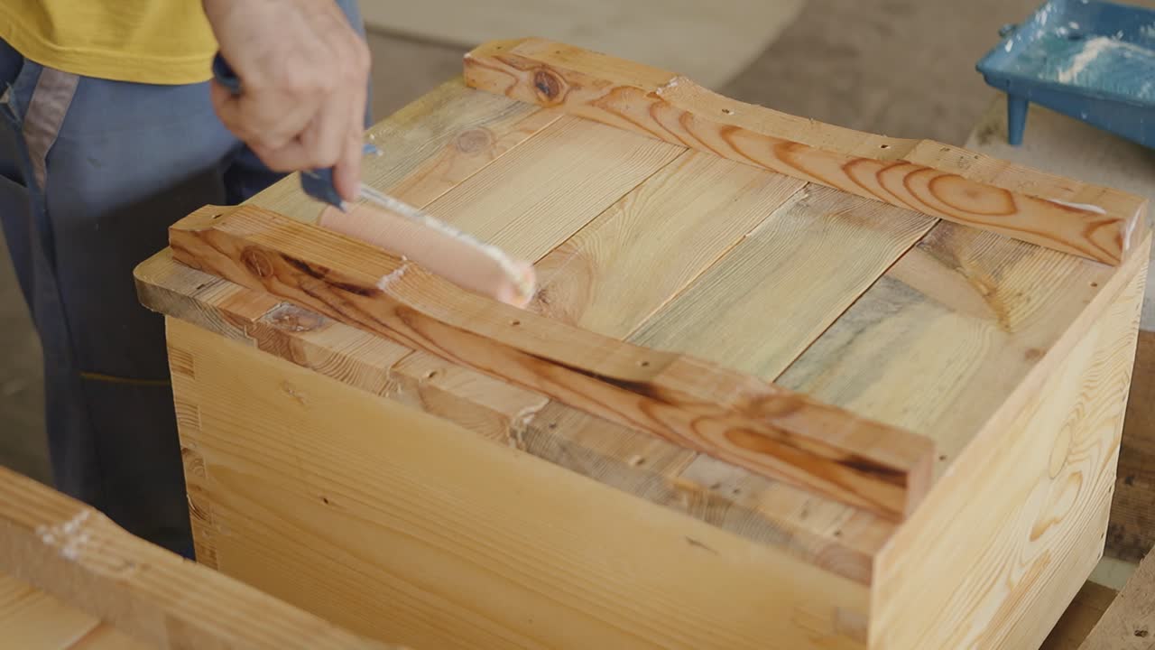 Un artigiano dipinge a mano una scatola di legno, concentrandosi sui dettagli e con cura.