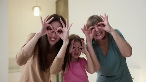 Photo-of-three-childish-positive-people-holding-hands-fingers-make-binoculars-for-fun