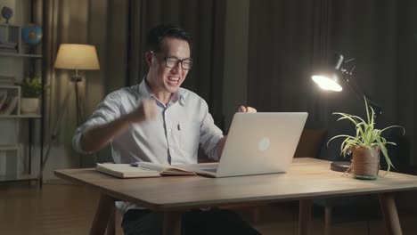 happy man working on laptop at night