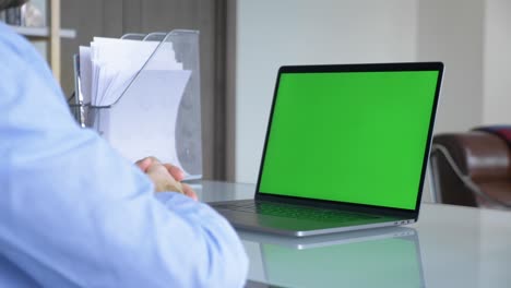 hombre de negocios escribiendo en un teclado de portátil con una pantalla verde en la pantalla de la computadora portátil