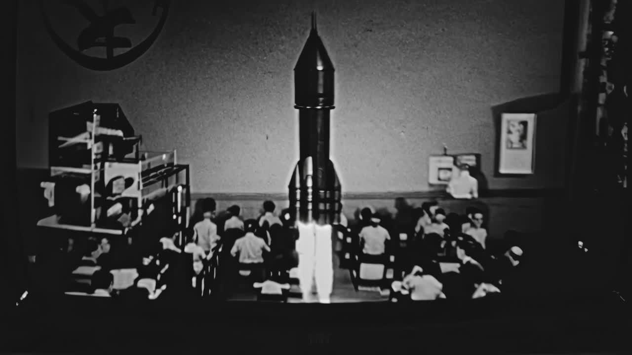 A vintage TV displays a black-and-white video in a dimly lit room