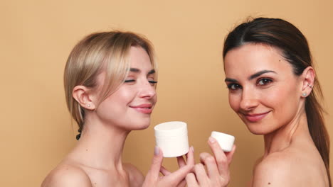 dos mujeres con productos para el cuidado de la piel