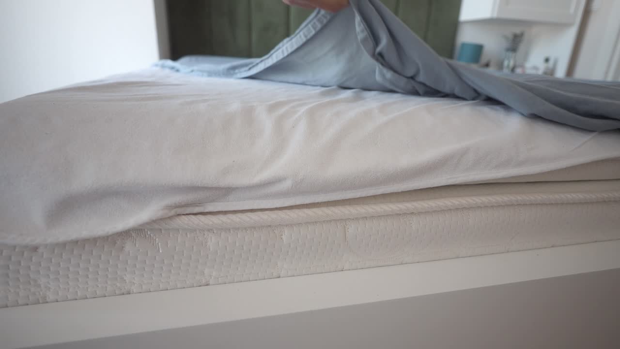 Close up of a bed with white sheets and blue duvet cover