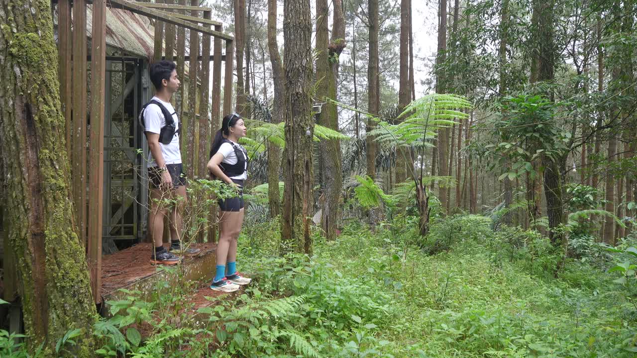 Asian couple resting and talking during outdoor workout in forest trail