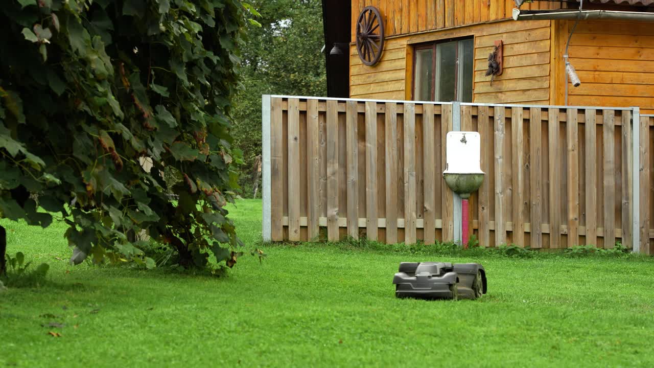 Smart autonomous electric robot lawn mower cutting lush green grass in yard