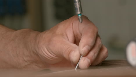 close-up of a person using a drill to screw in a wood workpiece.