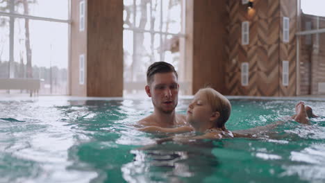 funny-little-girl-is-resting-in-pool-swimming-with-her-dad-and-laughing-happy-family-vacation