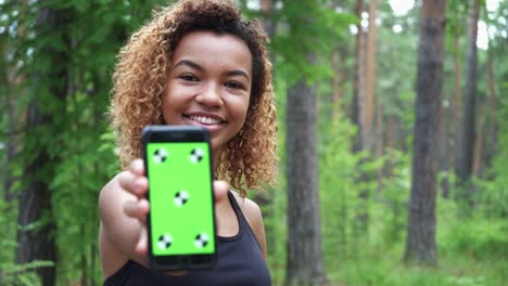 black young woman using her smartphone after jogging and shows green screen to the camera