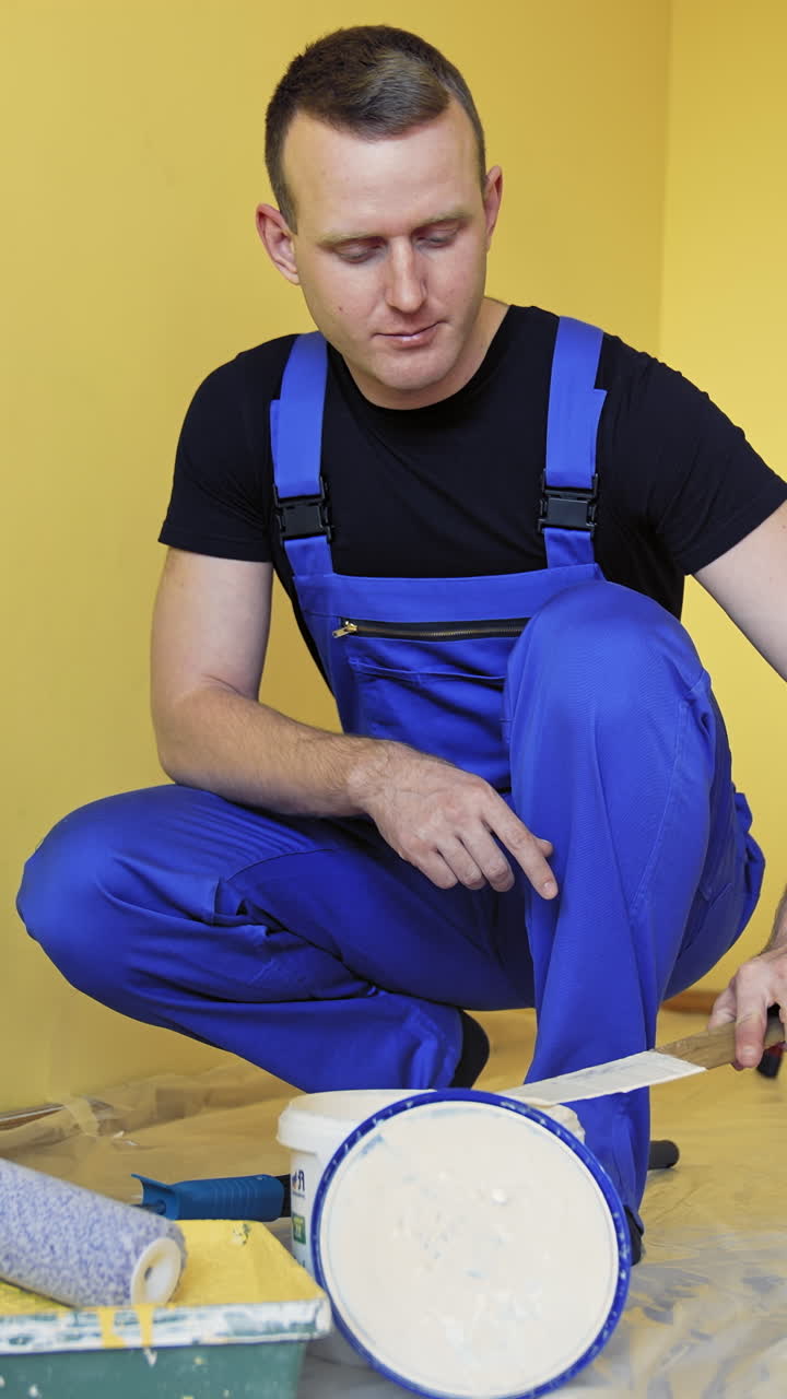 Handsome painting master doing room renovation. Professional painter renovating the room. Vertical video