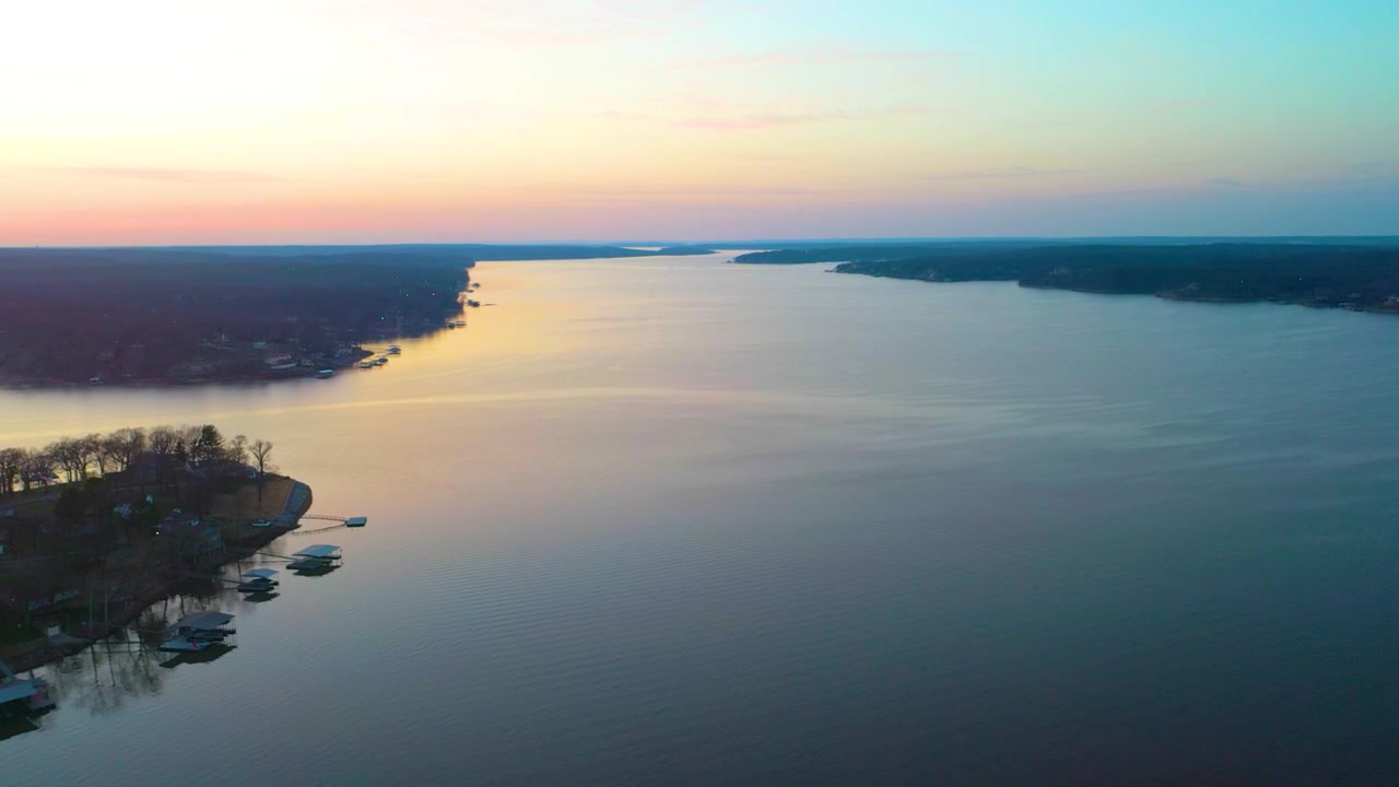 Ripresa con drone al tramonto sul lago Cumberland, Kentucky, con costa residenziale, rimesse per barche private, colline boscose, acqua calma del bacino e tenui riflessi dorati nella tranquilla luce del crepuscolo