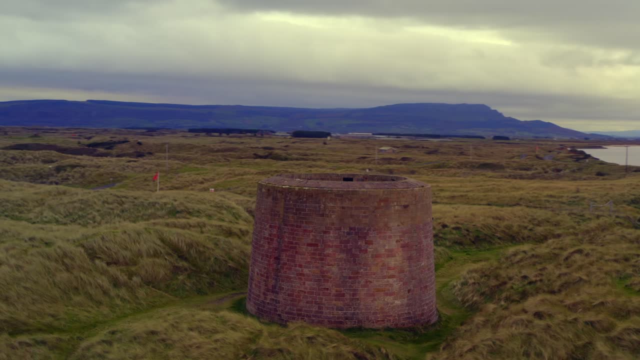 Aerial orbit around Magilligan Martello Tower, showcasing the surrounding landscape