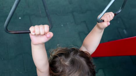 niño pequeño sosteniendo barras de metal en el patio de recreo