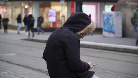 Imágenes-De-Un-Hombre-Mirando-Su-Teléfono-Mientras-Espera-El-Tren-O-El-Autobús