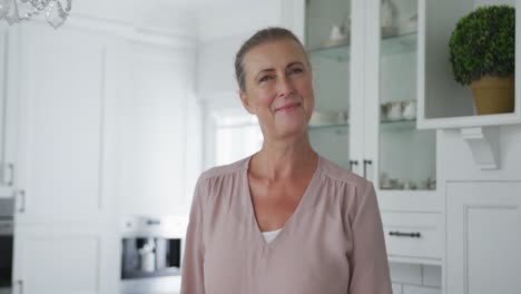 Portrait-of-smiling-senior-caucasian-woman-looking-at-camera-in-kitchen