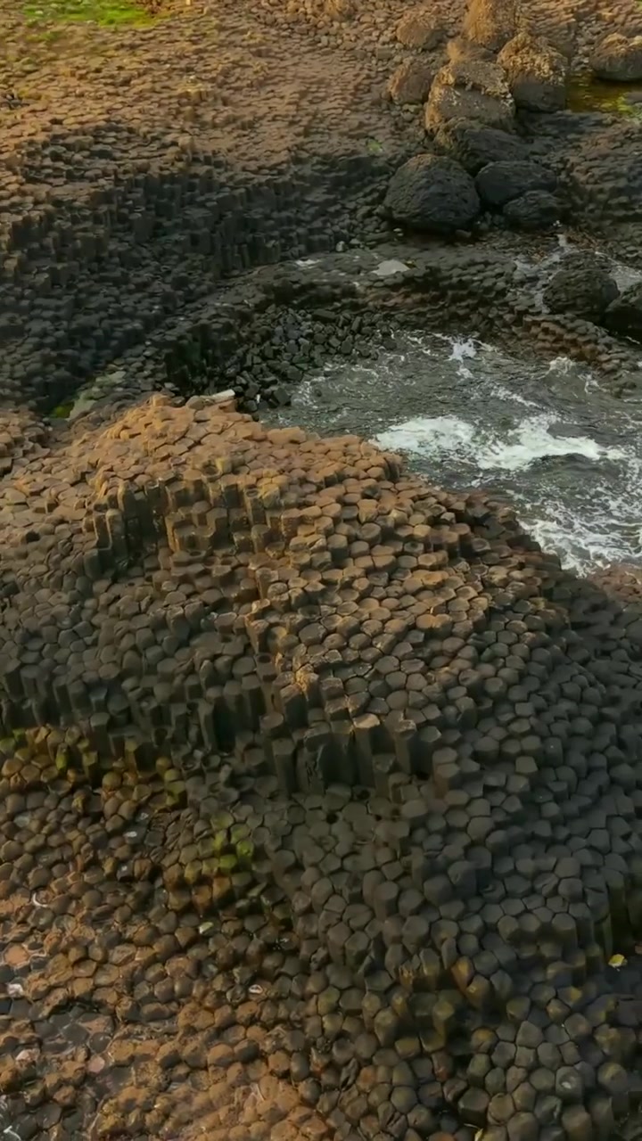 Video aereo in formato social delle colonne di basalto in pietra del Selciato del Gigante a Bushmills, Contea di Antrim nell'Irlanda del Nord, Regno Unito. Prodotto in formato verticale 1080x1920 con colore Rec709