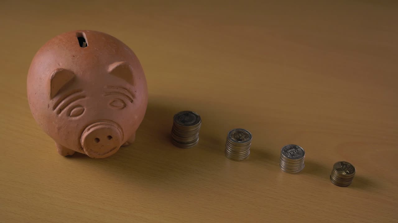 Clay piggy bank and stacks of colombian pesos coins