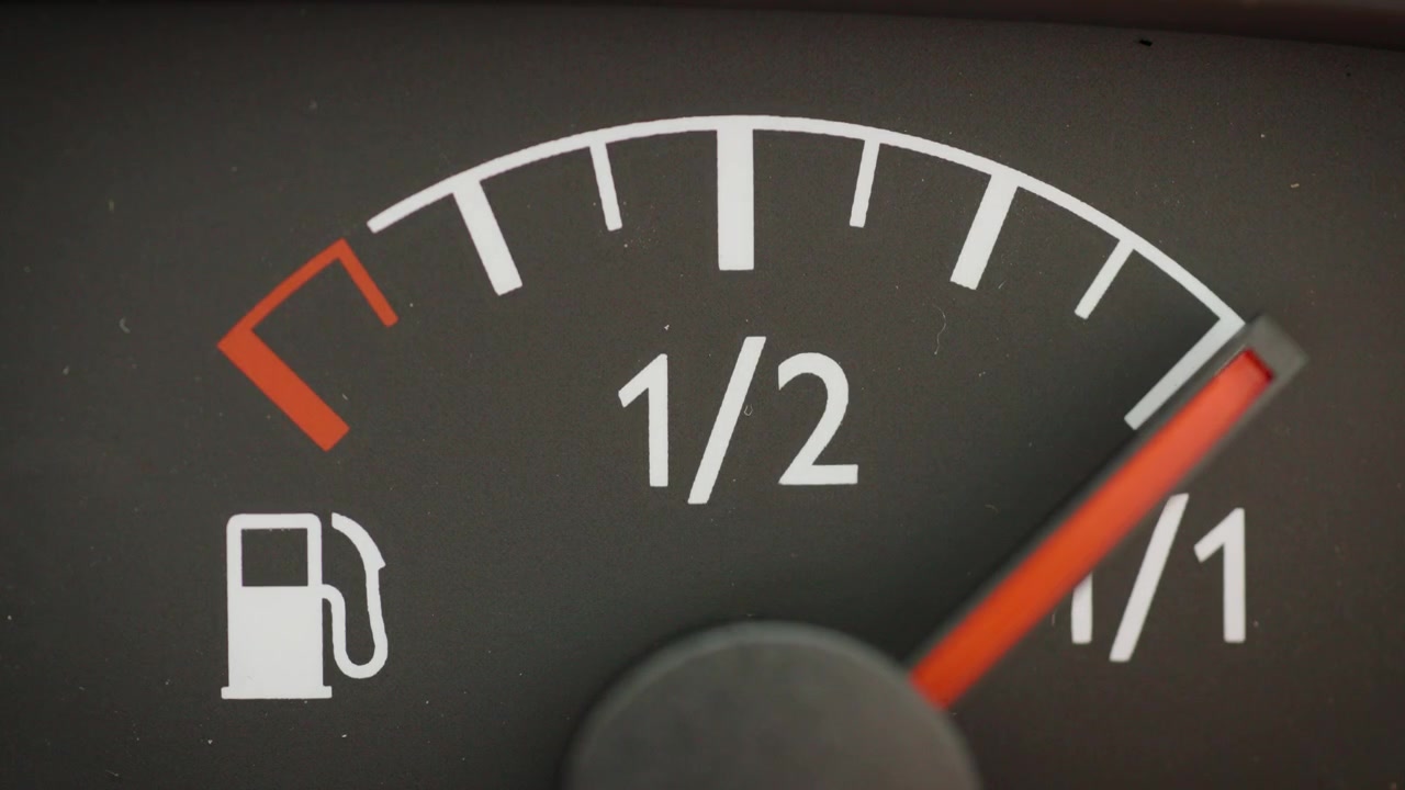 Macro shot of an automotive dashboard indicator with the needle rising to a full tank, conceptualizing refueling at a gas station or preparing for a road trip