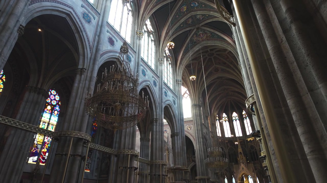 Panorámica del interior de la Iglesia Votiva de Viena, destacando su arquitectura neogótica y sus impresionantes vidrieras