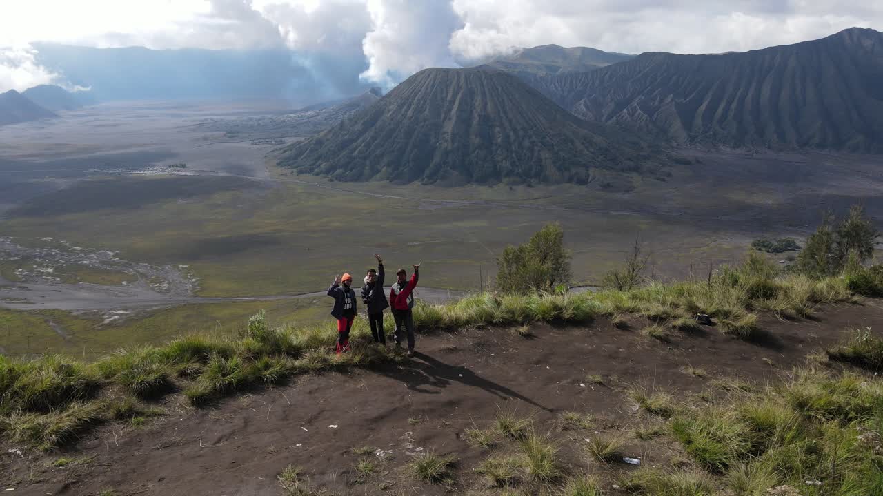 vista aérea, por la mañana, la zona del monte bromo y tres personas saludando al dron