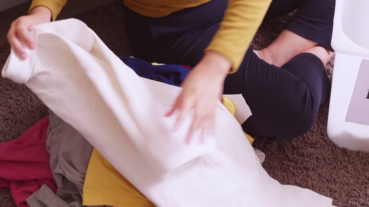 상자에 넣는 기부를 위해 옷을 정리하는 아시아 여성