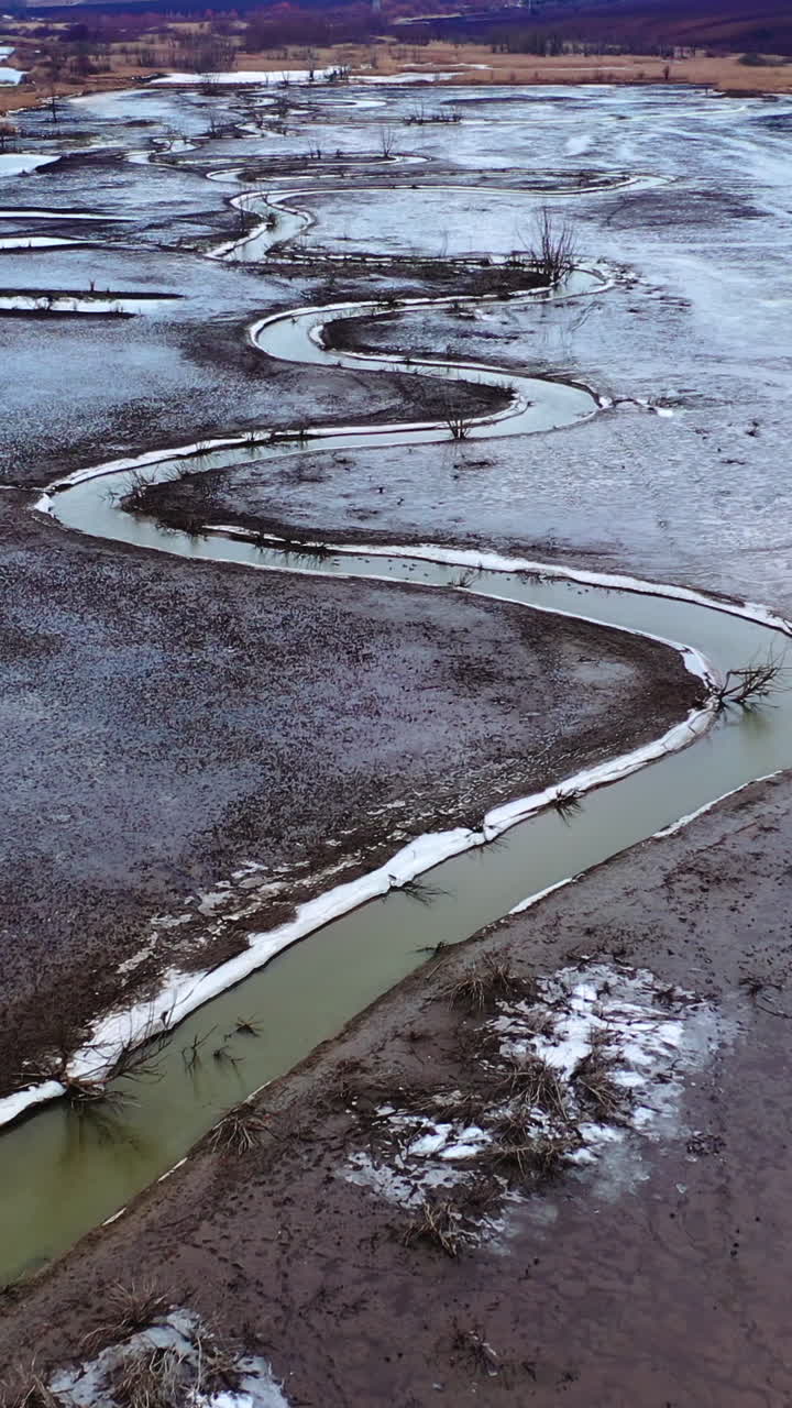 Narrow dirty river. Ecological problems with water. Dried place with a stream with muddy water floating in the countryside. Aerial view. Vertical video