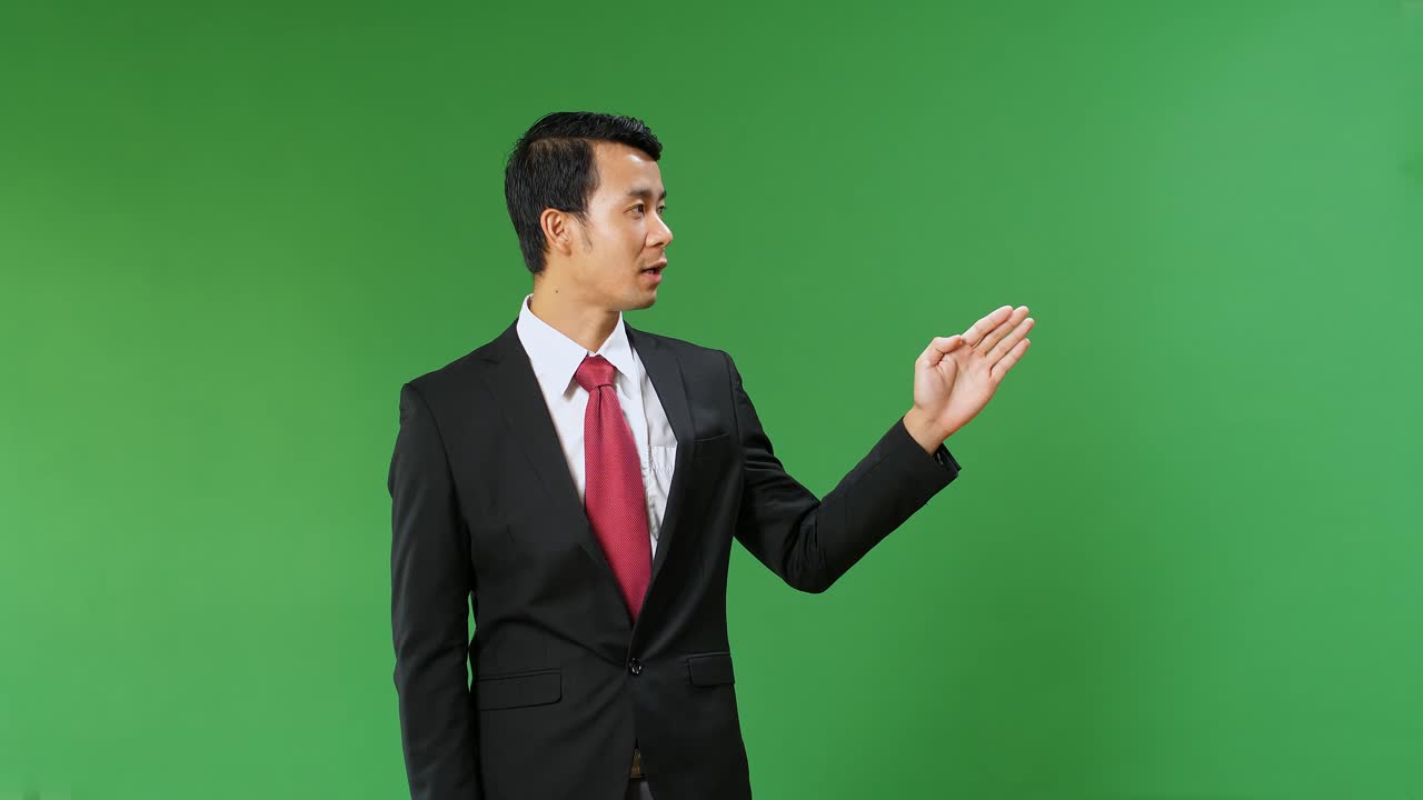 Asian Businessman Pointing On Something And Talking On A Green Screen, Chroma Key