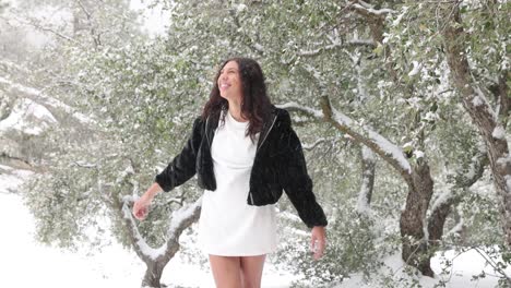 una mujer joven con un vestido corto se deleita con la nieve que cae a su alrededor
