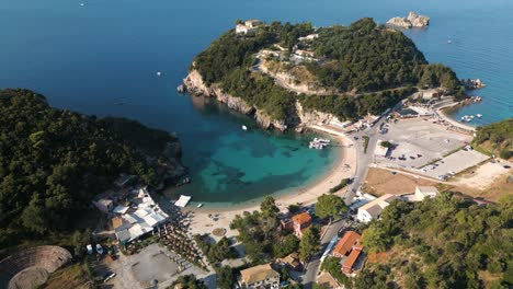 Un-Dron-Lento-Desciende-Sobre-Una-Cala-De-Arena-Con-Barcos-Atracados-En-La-Costa-De-Corfú,-Grecia