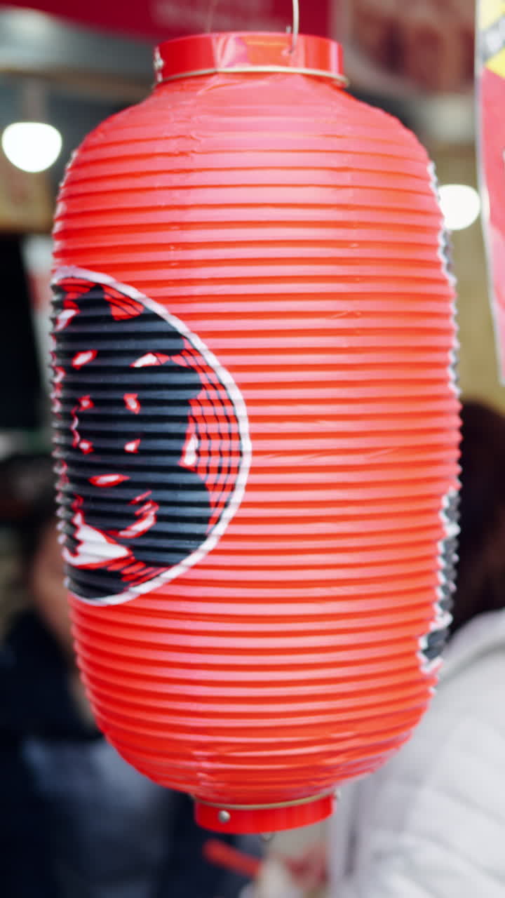 Close up of a red paper lantern with people in the background at the Tsukiji Fish Market in Japan. Vertical