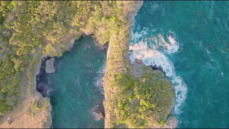 Aerial-top-down-shot-of-beautiful-coastline-with-waves-in-Samana-with-famous-hondonada-arch-during-golden-sunset-in-Dominican-Republic---rising-drone-shot