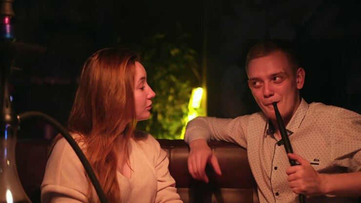 Coppia che fuma narghilè in un bar di notte